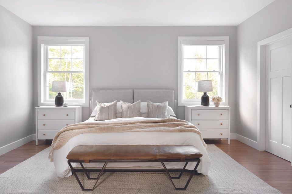 Gray bedroom with cozy, comfortable furniture and white nightstands.